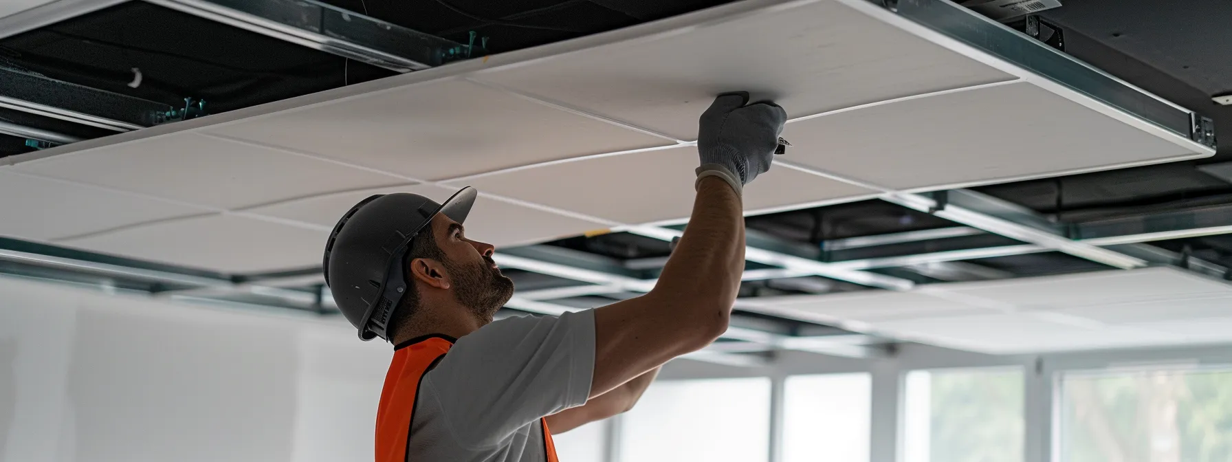 a professional installer carefully placing sleek, sound-absorbing acoustic ceiling panels in a modern office space.